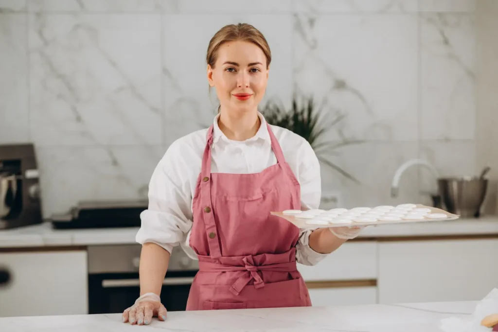 About Me 1 Clara Hayes holding a tray of homemade macarons in a modern home kitchen